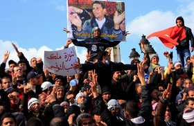 Tunisian protesters demonstrating beneath a poster of Mohamed Bouazizi