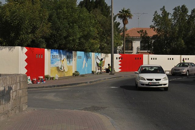 Near the ‘Bulls head’ roundabout in Sehla, Bahrain, a ‘beautification’ team paint walls with images of pearl divers, dhows and oysters.  Photograph by Amal Khalaf.