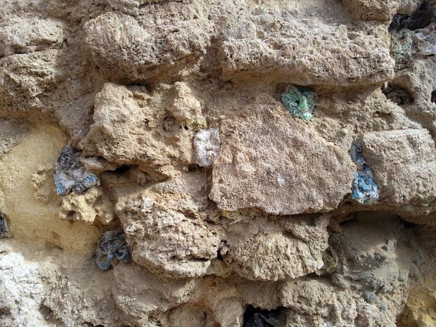 A wall in the city of Zwara, where holes have been filled with coloured plastic bags and then eroded by either wind or sun or eaten by goats. Photograph by Hadia Gana, November 2011. Courtesy and © Hadia Gana. 