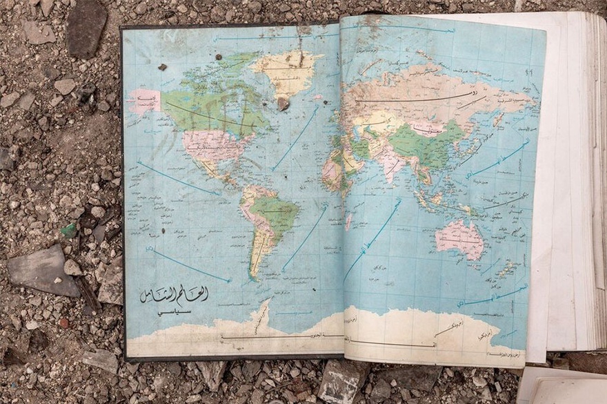 Carole Alfarah. An old world map inside a book found in the rubble in a destroyed neighborhood in Homs with Arabic writing ‘The Global World. Political’. Homs, Syria, 2014. 