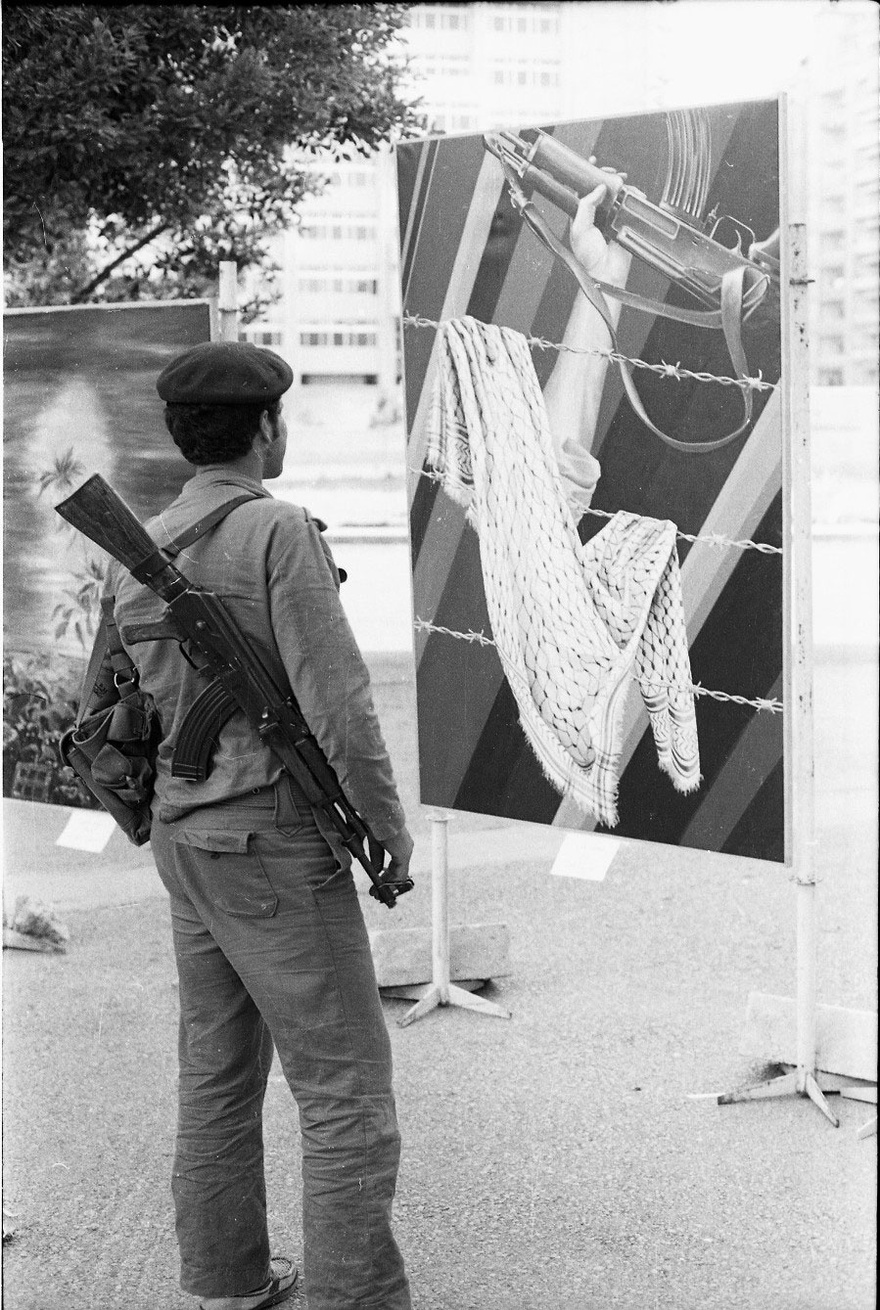 Palestinian fighter looking at artwork by Claude Lazar at 15 May Exhibition, Day of the Palestinian Struggle, Beirut, 1978.